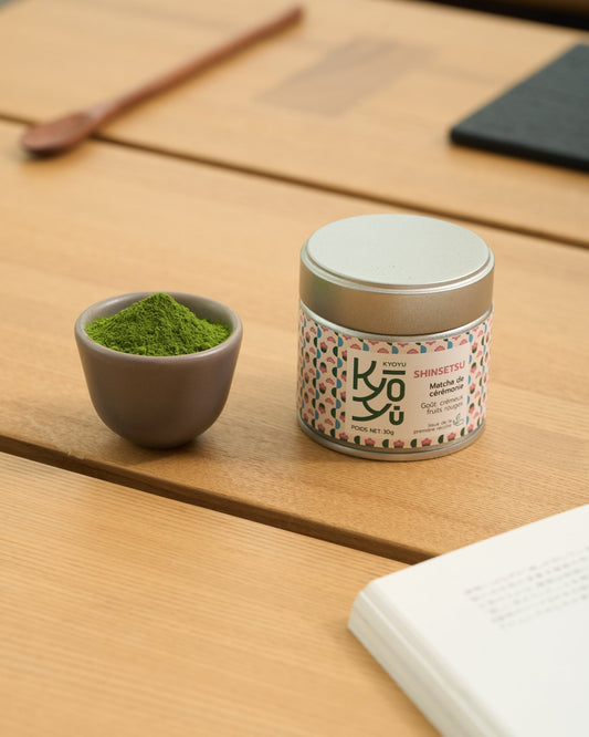 Kyoyu matcha Shinsetsu, goût Umami, crémeux aux subtiles notes de fruits rouges. il est posé sur une table et juste à côté se trouve une coupelle remplie de matcha.